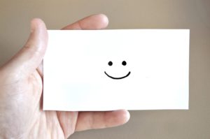 Hand holding a note with a smiley face