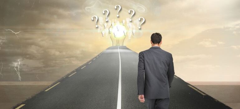 Businessman walking a pat toward ideas with questions marks.