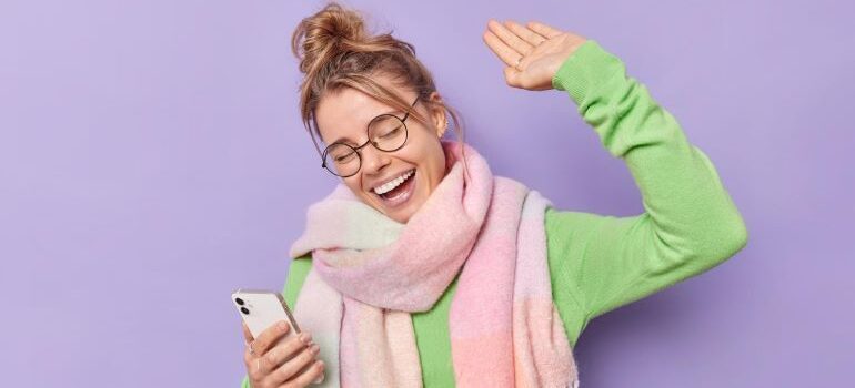Woman holding a phone and smiling.