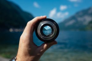Hand holding a lense with the sea in the background - look at what you need for borrowing images online.
