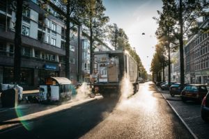 Moving truck packed with boxes and supplies driving down the street into the sunset - a smooth start of a successful moving company.