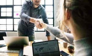 People shaking hands with a company growth plan on a laptop.
