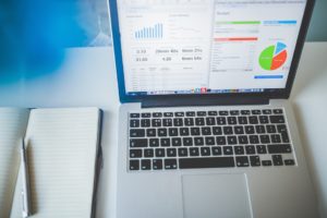 Notebook and laptop with numbers and stats.
