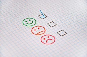 Three different faces drawn on a piece of paper; the happy face is checked.