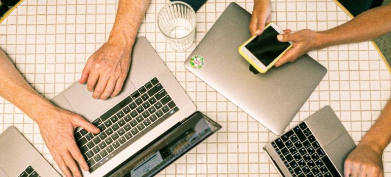 People at table with laptops and smartphones.