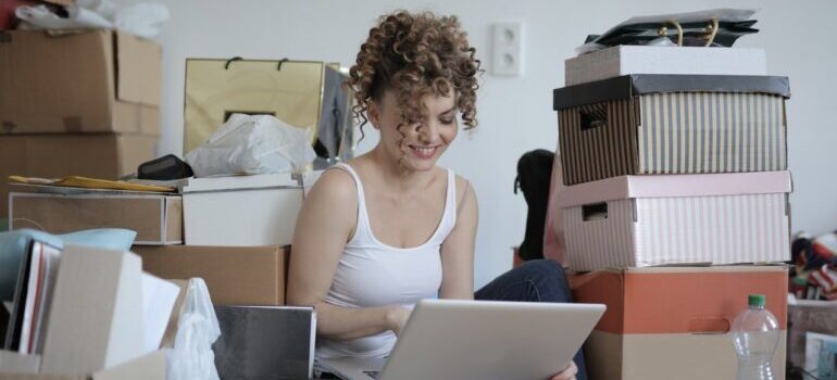 Woman with laptop, surrounded by boxes