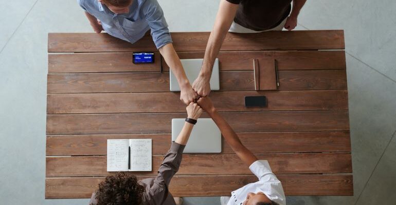 Four people with their hand bumping fists.
