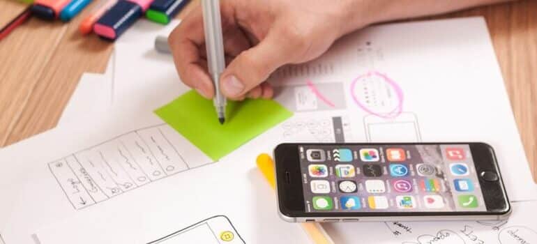 A person designing a website on paper next to a mobile device.