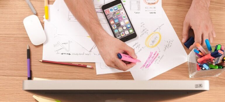 a hand holding a pink highlighter crossing off phrases written on a piece of paper