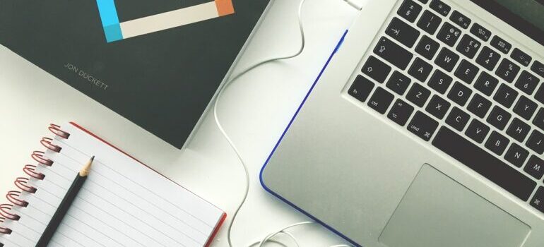 a keyboard of a laptop computer next to a notebook with a pencil on it