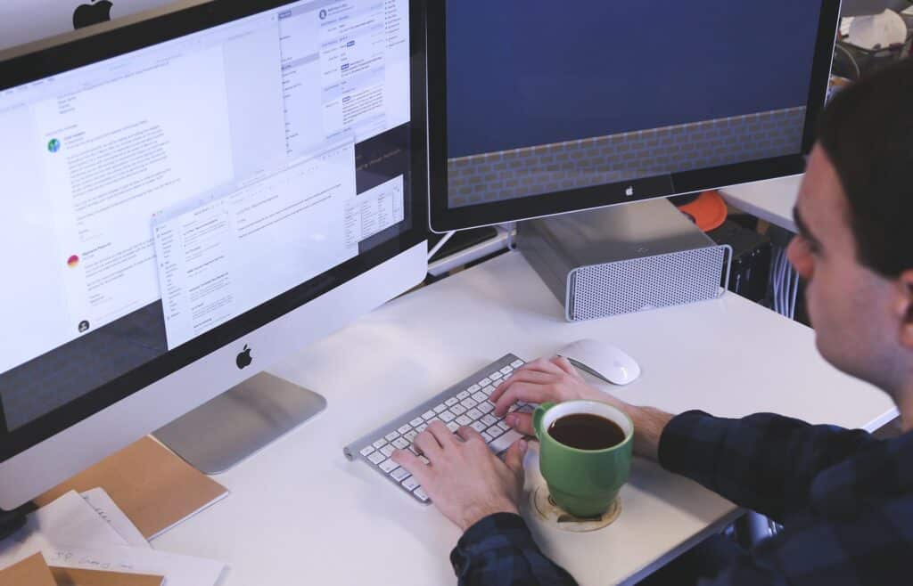A person typing in front of two monitors