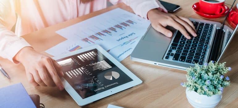 Person typing on keyboard while looking at graphs and charts.