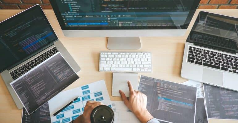 Person coding a website on three screens.
