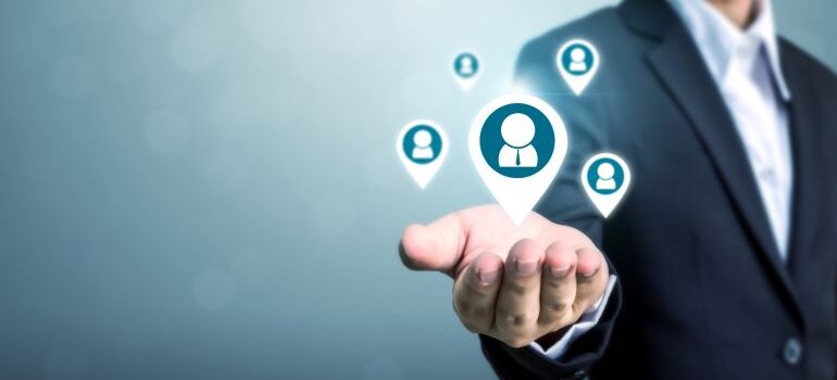 Businessman holding a customer icon in the palm of his hand.