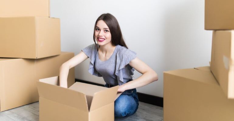 A happy girl, surrounded by moving boxes.