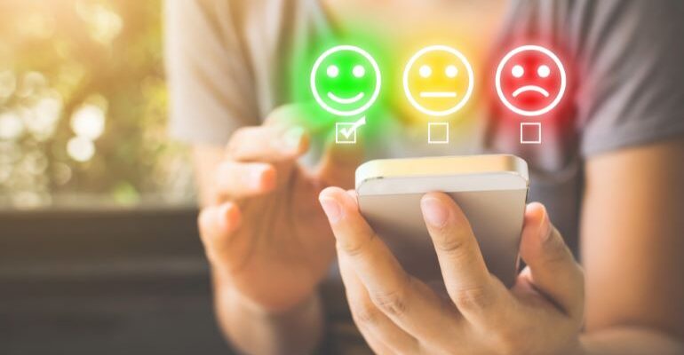 Person holding a phone, with opinion emojis above it.