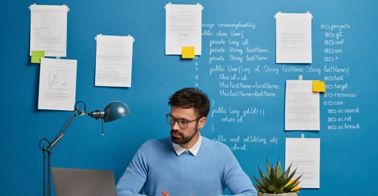 Person looking at laptop, with analytics behind him.