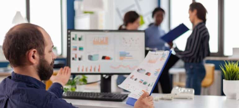 Person looking at charts in hand and on screen.