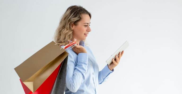 Woman holding shopping bags and looking at her phone.