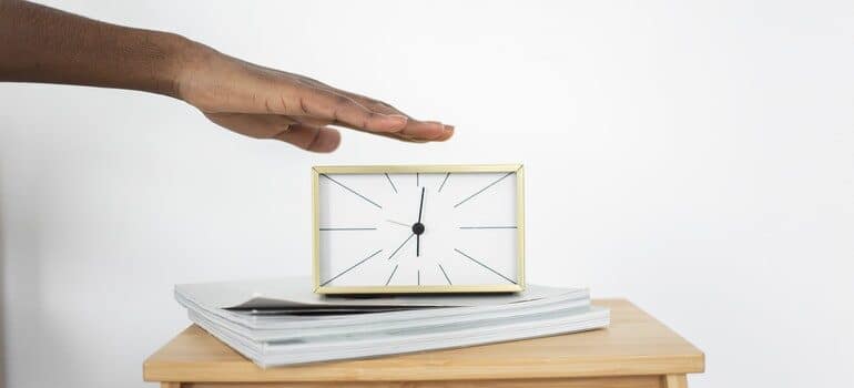 Person turning off an alarm on a clock.