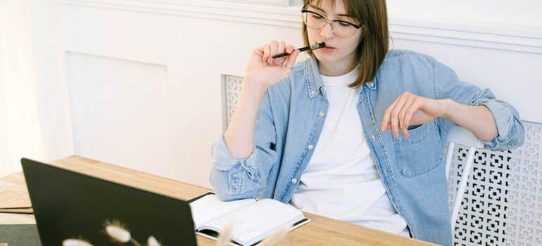 Woman looking at a laptop with a thoughtful expression.