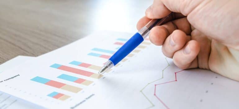 Person's hand with a pen pinting at a graph