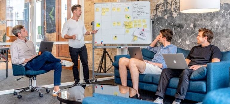 A marketing team of four people having a meeting about audience research tools in an office with glass doors