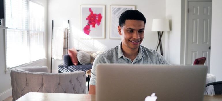Man sitting at a desk with his laptop in front of him and smilling