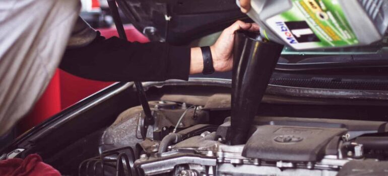 A person oiling a moving tucks engine.