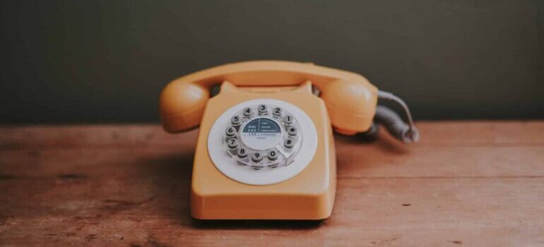 An orange telephone on a desk.