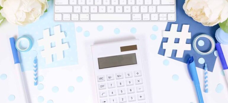 Hashtag signs made out of paper positioned on a desk next to a calculator and keyboard