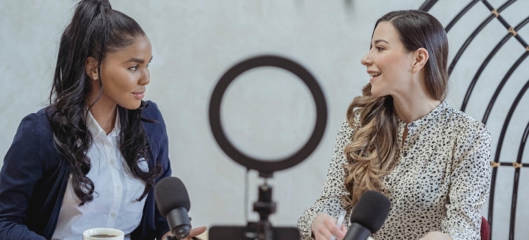 Two women recording a podcast about social proof can drive more business for your moving company