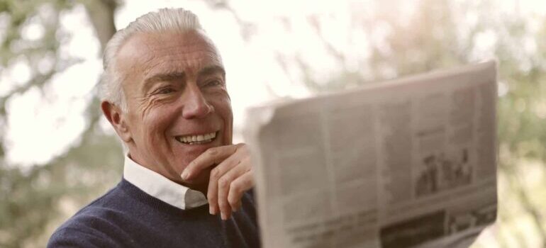 Elderly man reading newspaper outside
