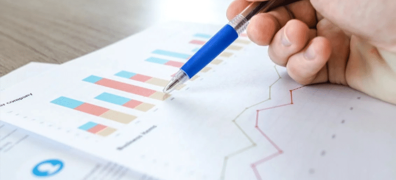 A person pointing at graphs on a sheet of paper, illustrating how moving companies need to base services on what people in major cities want from movers over time.