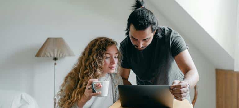 Two people searching for moving companies on their laptop