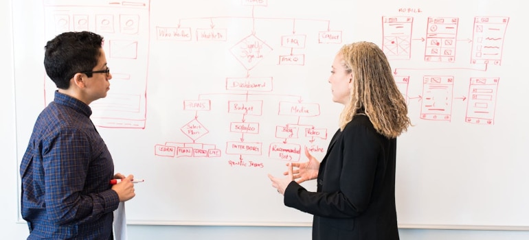 two people discussing something near a whiteboard