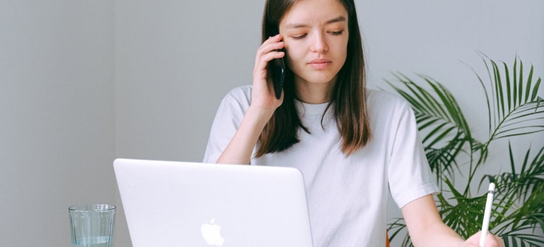 a woman writing something down while on a phone call and discussing digital communication in the moving industry