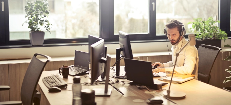 The man sitting on his desk with his headphones talking to his clients is one of the ways of how to keep up with moving industry standards.