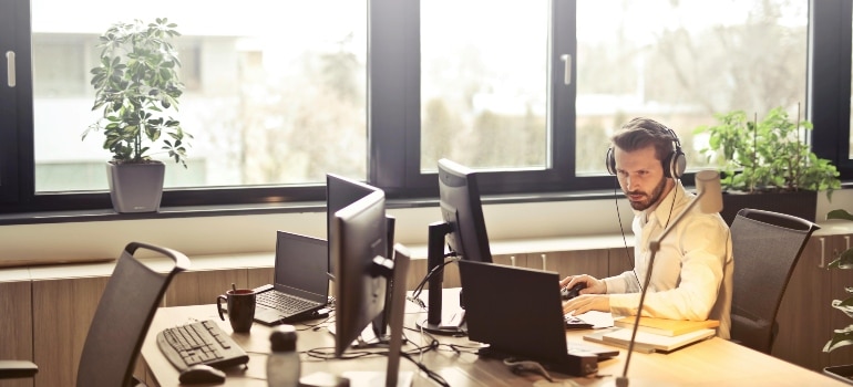 Man With Headphones Facing Computer Monitor
