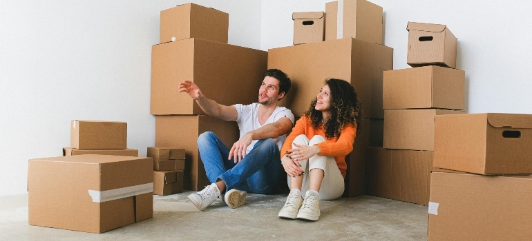 Two people sitting by a pile of boxes. 