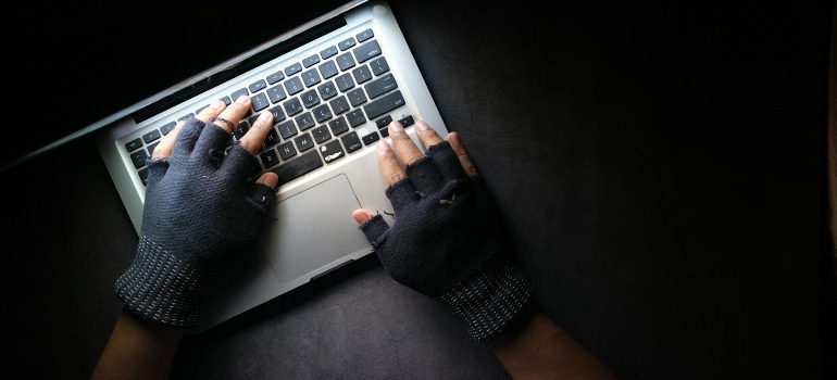 person wearing gloves typing on a laptop