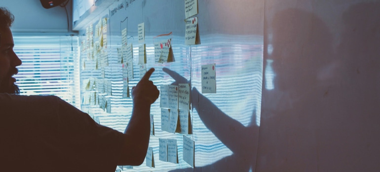 man pointing at sticky notes on a whiteboard and discussing limitations of relying on freelancers 