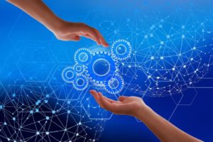 Two hands reaching out to wheels turning, with a network of connected dots in the background.