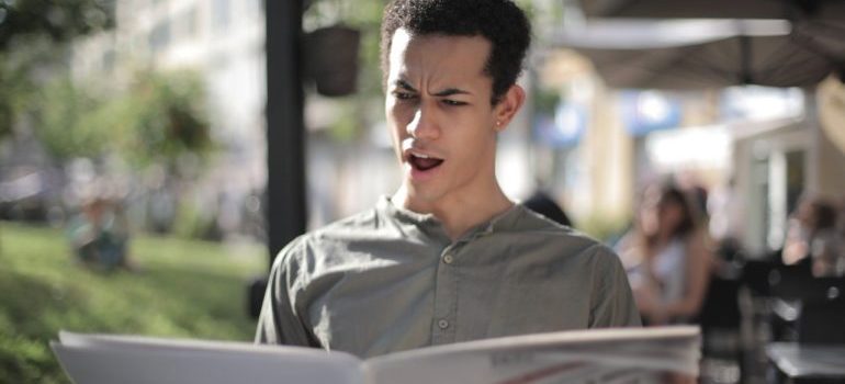 Person reading newspaper with shocked expression