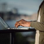 Person typing on a laptop outdoors.