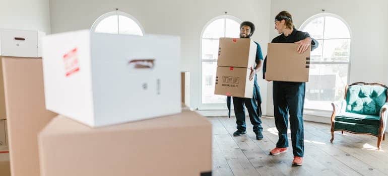 Two employees of a moving company carrying boxes