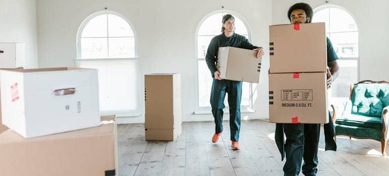 Two employees of a moving company carrying boxes
