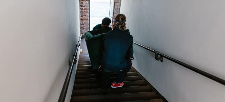 Two moving company employees carrying a couch