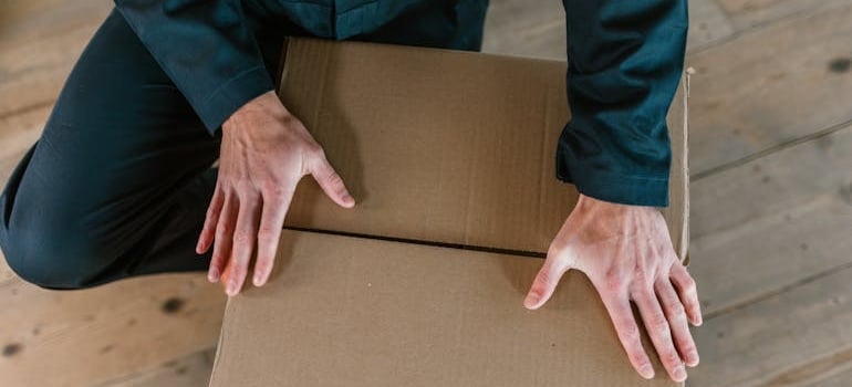 A moving company employee closing a carton box